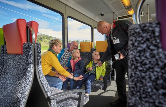 Familie reist im Thurbo Zug und ein Kundenbegleiter kontrolliert ein Kinderbillett.