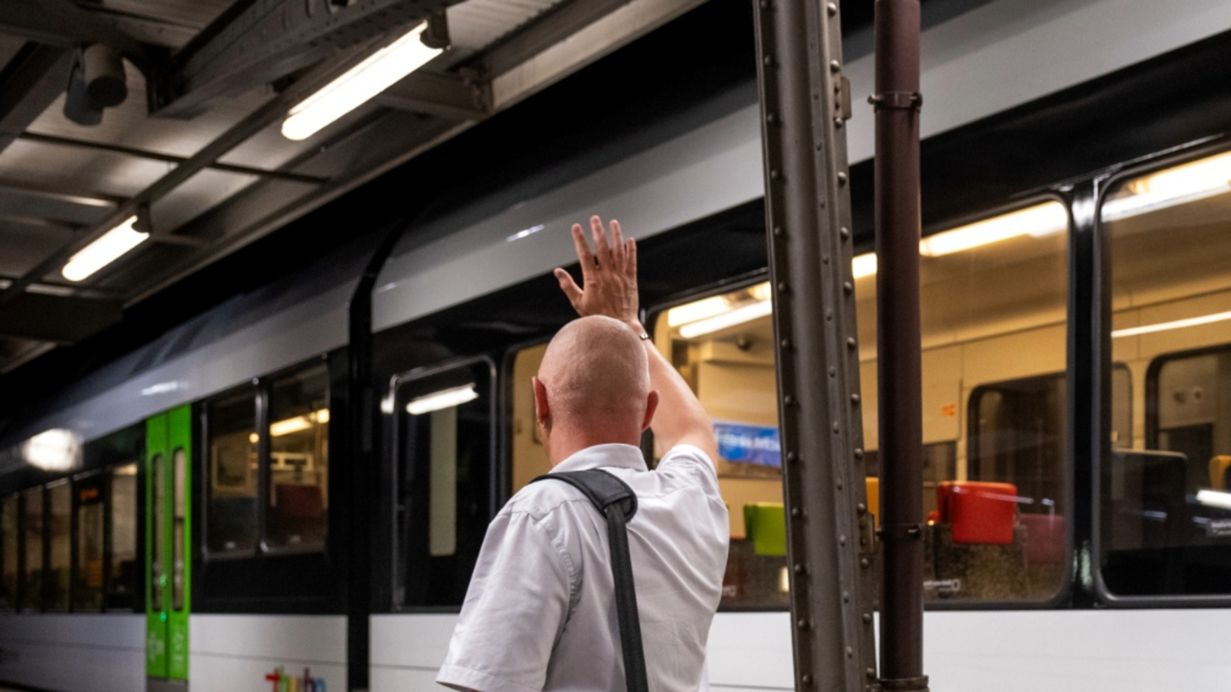 Kundenbegleiter vor einem Thurbo Zug winkt jemanden.
