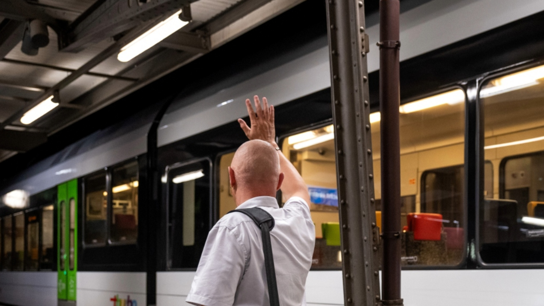 Kundenbegleiter vor einem Thurbo Zug winkt jemanden.