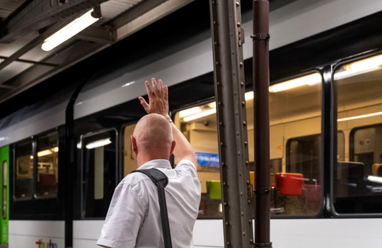 Kundenbegleiter vor einem Thurbo Zug winkt jemanden.