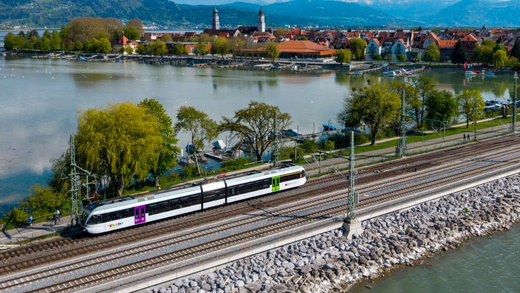 Thurbo Zug fährt direkt auf eine Halbinsel. Im Hintergrund eine Stadt.