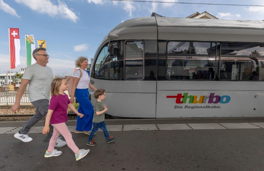Familie läuft im Bahnhof auf ein Thurbo Zug zu.