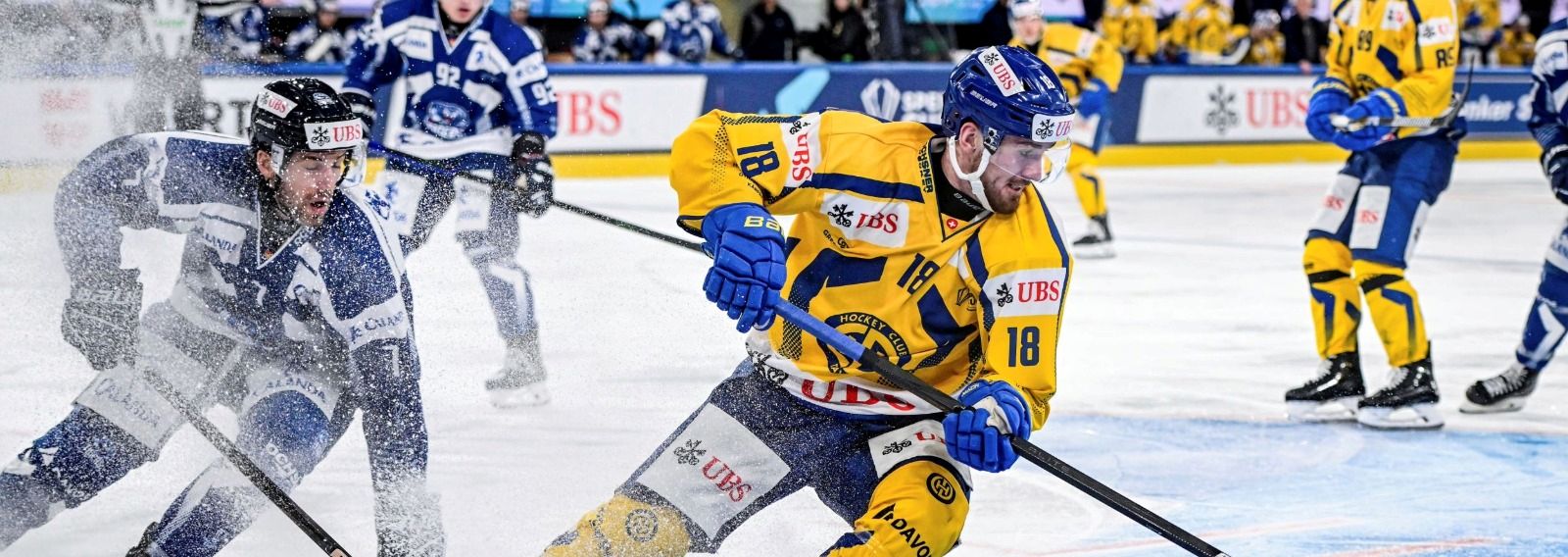Eishockeyspieler im Einsatz mit stäubendem Eis.
